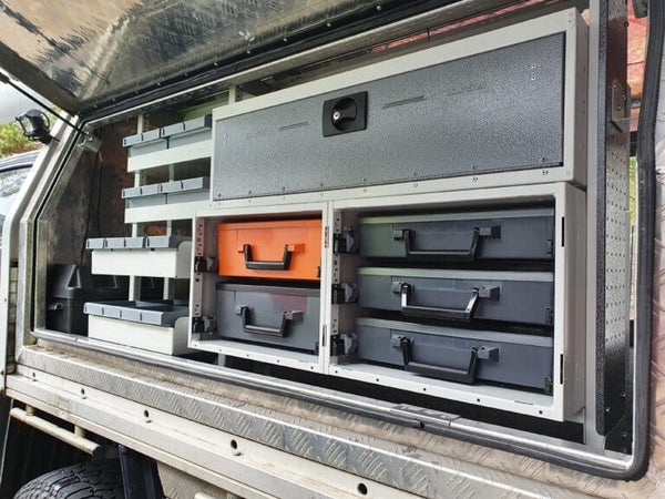 Storage system with drawers and compartments on a vehicle's open cargo area.