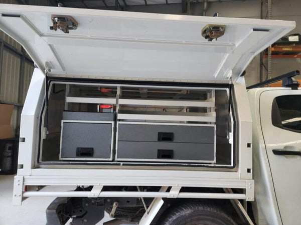 Open storage compartment of a vehicle with drawers and compartments.