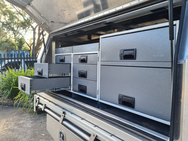 Storage drawers and cabinets in a vehicle's cargo area with outdoor setting.