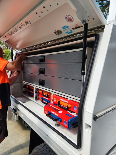 Open storage compartment with shelves and boxes inside, person reaching in.